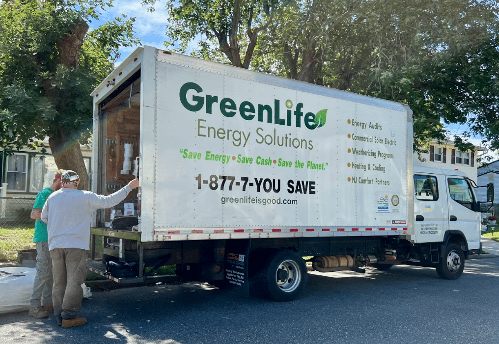 two workers standing outside of a work truck